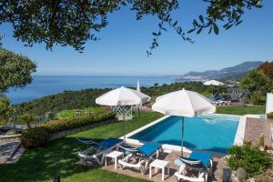 una piscina con sillas y sombrillas y el océano en Villa Montefontane, en Camporosso