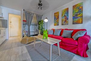 a living room with a red couch and a table at T2 cosy de 41m2 à 400 m de la plage, résidence avec piscine. in Le Grau-du-Roi