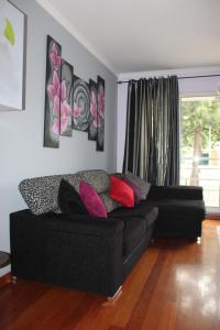 a living room with a black couch and a window at Uptown Madalenas in Funchal