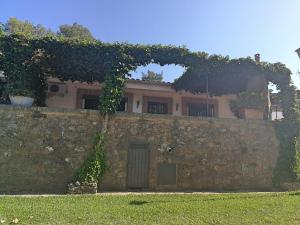 una casa dietro un muro di pietra con una porta di Casa Rural La Presa a Valdeobispo