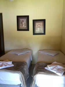 two beds in a hotel room with white walls at Hotel Fazenda Santa Maria in Serra Negra