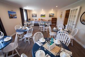 a dining room with blue tables and white chairs at Alphabet Fleet Inn in Twillingate