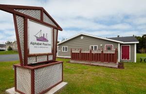 a sign in front of a house with a boat on it at Alphabet Fleet Inn in Twillingate