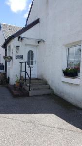 a white building with stairs leading to a door at The Old School in Salen