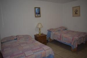 Un dormitorio con dos camas y una lámpara sobre una mesa. en Blanquita guesthouse, en Manuel F. Martínez