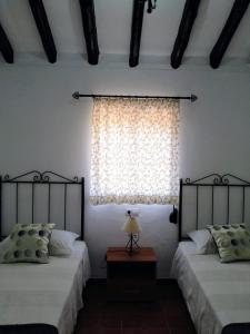 a bedroom with two beds and a window at Alojamiento Rural El Orégano in Campillos