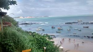 a group of people on a beach with boats in the water at Casa de Nylva Beach Pipa in Pipa