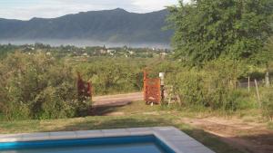 a swimming pool next to a road with a mountain at Cabaña El Mirador de Bialet Masse in Villa Parque Siquiman