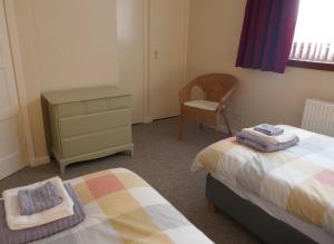 a bedroom with two beds and a dresser and a chair at Inverness Family House in Inverness