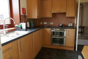 una cocina con armarios de madera y fregadero en Inverness Family House, en Inverness