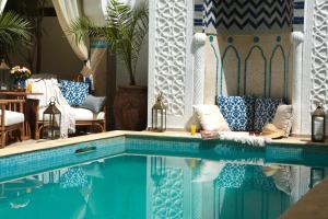 a swimming pool with blue and white pillows and a table at Riad Dar Alfarah in Marrakesh