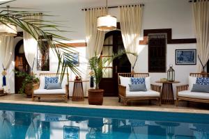 a poolside living room with chairs and a table at Riad Dar Alfarah in Marrakesh