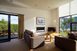 sala de estar con 2 sillas y chimenea en The Fairways Luxury Accommodation Kaikoura, en Kaikoura