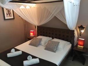 une chambre avec un lit avec des draps blancs et des oreillers dans l'établissement Domaine de l'Anse des Rochers, à Saint-François