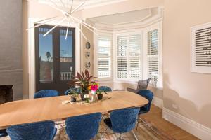 a dining room with a wooden table and blue chairs at Franklin38 in Auckland