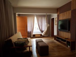 una sala de estar con un sofá y un televisor en Casa piscina próxima praia, en Florianópolis