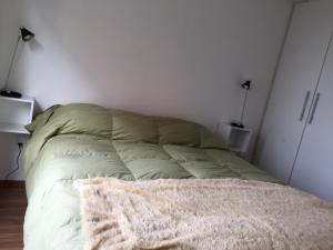 uma cama num quarto com uma parede branca em Palm Beach em Montevidéu
