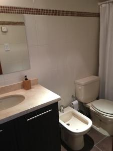 uma casa de banho com um lavatório, um WC e um espelho. em Palm Beach em Montevidéu
