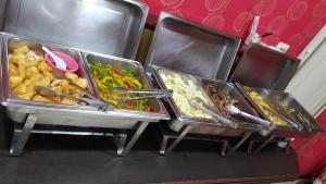 three trays of food with tongs and different foods at Treasure Island Motel - Fengshan in Kaohsiung