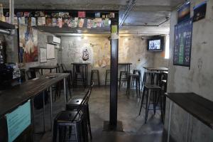 a bar with tables and stools in a room at Time Travelers Party Hostel In Hongdae in Seoul