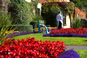 a woman walking through a garden with flowers at The Dunraven, Adare in Adare