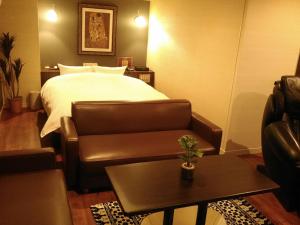 a bedroom with a bed and a couch and a table at Hotel Dio (Adult Only) in Osaka
