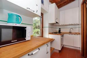 a kitchen with white cabinets and a microwave at Agriturismo Pimpinnacolo in Porto Ercole