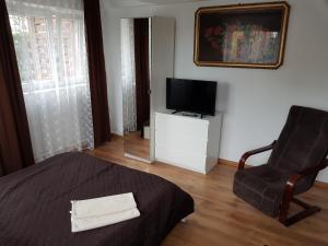 a bedroom with a bed and a chair and a television at Apartamenty Nadmorskie in Władysławowo