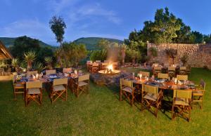 an outdoor dining area with tables and chairs and a fire pit at Shamwari Bayethe in Paterson