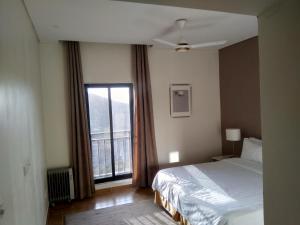 a bedroom with a bed and a large window at Beit Al Ward in Ash Shafa
