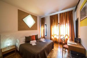 コッレ・ディ・ヴァル・デルザにあるLa Vecchia Cartieraのベッド、デスク、窓が備わるホテルルームです。
