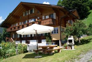 ein Haus mit einem Regenschirm und einem Picknicktisch davor in der Unterkunft Am Eigen in Grindelwald