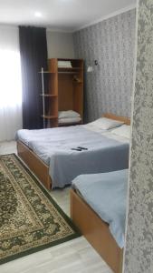 a bedroom with two beds and a book shelf at Отель Мармелад Иссык-куль in Bosteri