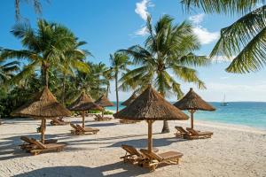 a group of straw umbrellas and chairs on a beach at Zuri Zanzibar in Kendwa