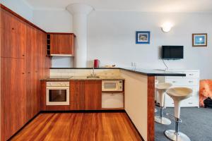 a kitchen with wooden cabinets and a counter top at Viaduct Loft 2BR Delight with Netflix and Aircon in Auckland