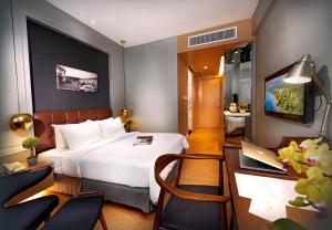 a hotel room with a bed and a desk with a laptop at Kingwood Boutique Hotel in Miri
