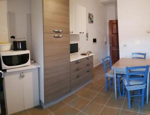 eine Küche mit einem Tisch, blauen Stühlen und einer Mikrowelle in der Unterkunft Piero's Apartment Cardedu in Cardedu