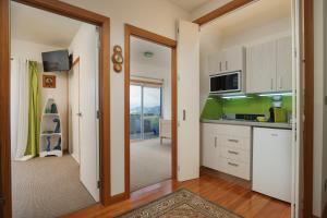 a kitchen with white cabinets and a door leading to a balcony at Paku Palms in Tairua