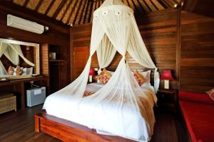 a bedroom with a bed with mosquito netting at Dream Beach Cottages in Nusa Lembongan