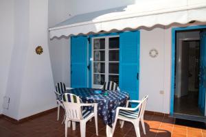 una mesa y sillas en un porche con puertas azules en Anemos en Spetses