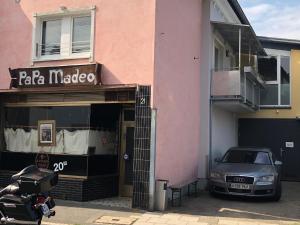 une voiture garée devant un bâtiment rose dans l'établissement Apartment Köln Ensen, à Cologne