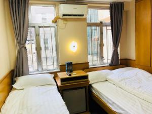 two beds in a room with two windows at Good Fortune Inn in Hong Kong