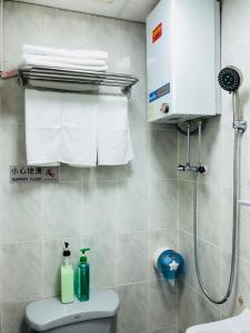 ein Bad mit einer Dusche, einem WC und Handtüchern in der Unterkunft Good Fortune Inn in Hongkong