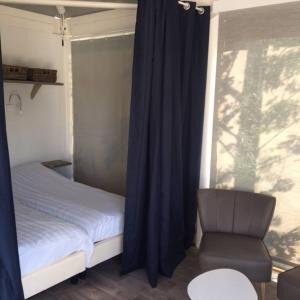 a bedroom with a bed and a chair and a window at Safaritent glamping tent nabij Sint Maartenszee in Sint Maartensvlotbrug
