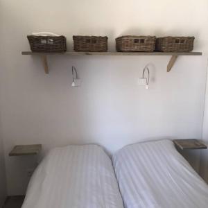 duas camas num quarto com cestos na parede em Safaritent glamping tent nabij Sint Maartenszee em Sint Maartensvlotbrug