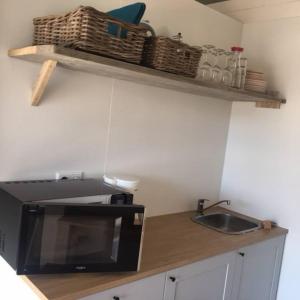 a kitchen with a counter with a microwave and a sink at Safaritent glamping tent nabij Sint Maartenszee in Sint Maartensvlotbrug