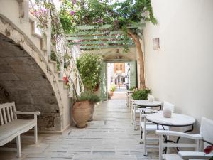 a patio with tables and chairs and an archway with plants at Mythos Suites Boutique Hotel in Rethymno