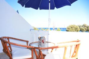 a table and a chair and an umbrella on a balcony at Kiotari Beach Apartments in Kiotari