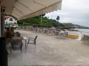 a restaurant with tables and chairs and a view of the water at Pensión El Tabanu in Celorio