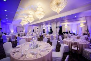 a ballroom with white tables and chairs and chandeliers at Tsarsko Selo Spa Hotel in Sofia